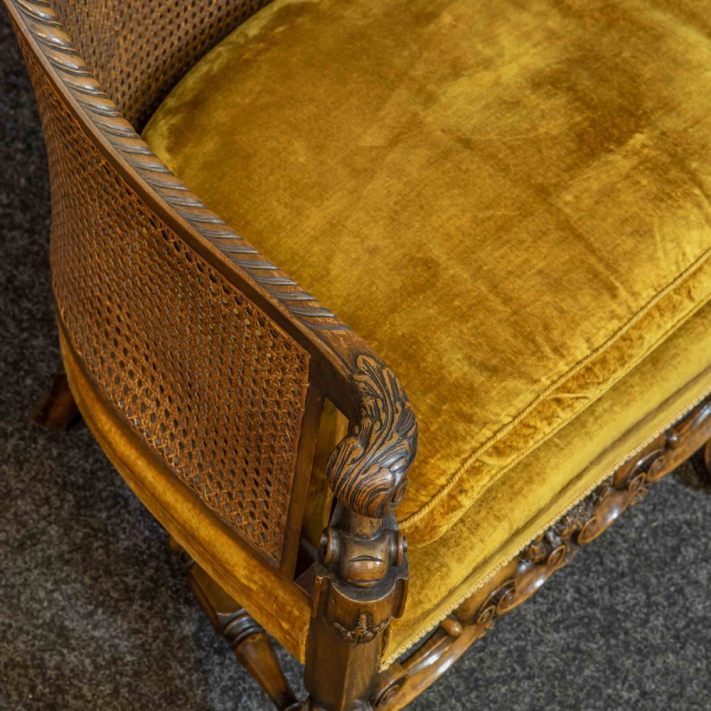A William and Mary style walnut sofa featuring a high curved woven cane backrest, gold velvet cushion seat, and intricately carved scrollwork base. View VII