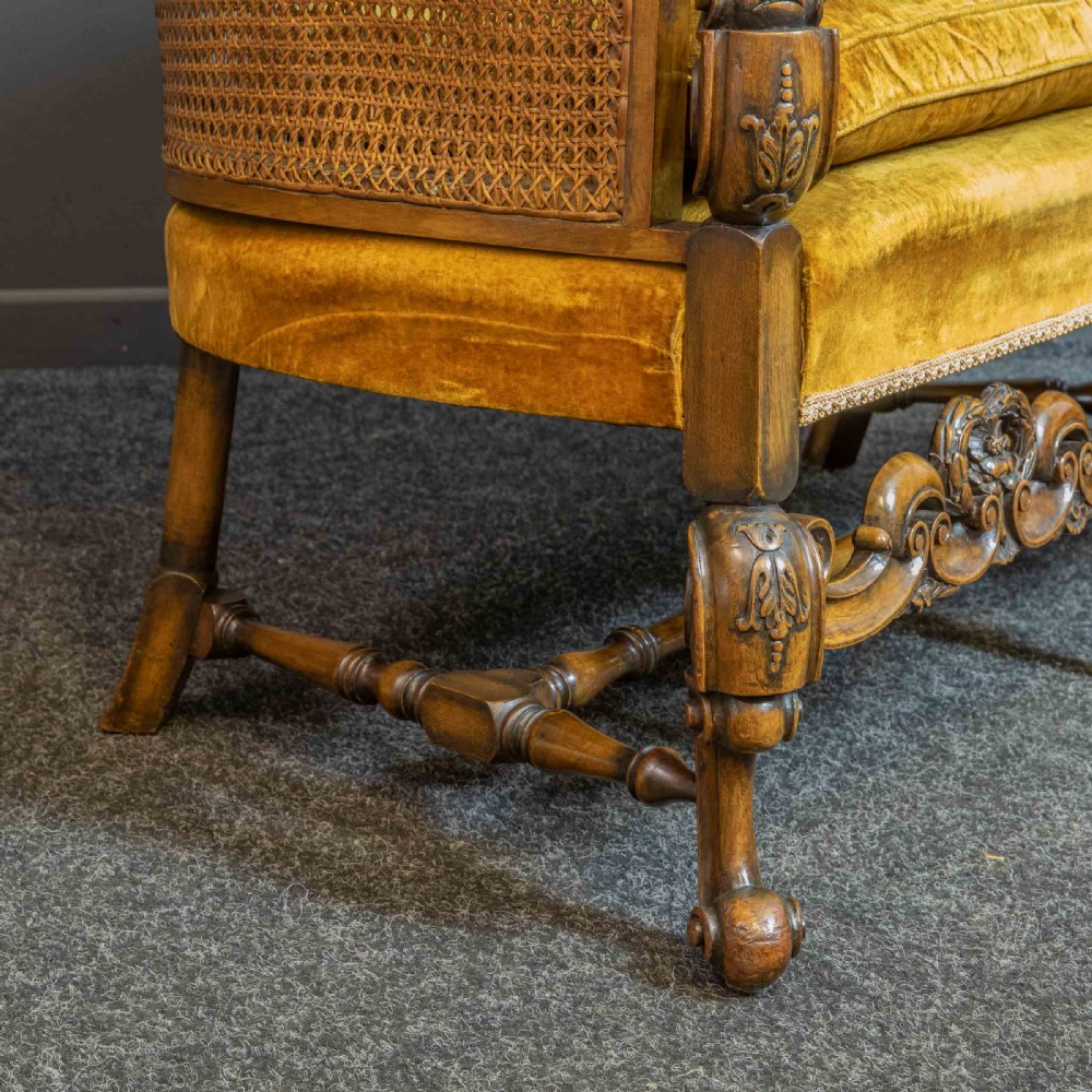 A William and Mary style walnut sofa featuring a high curved woven cane backrest, gold velvet cushion seat, and intricately carved scrollwork base. View XI