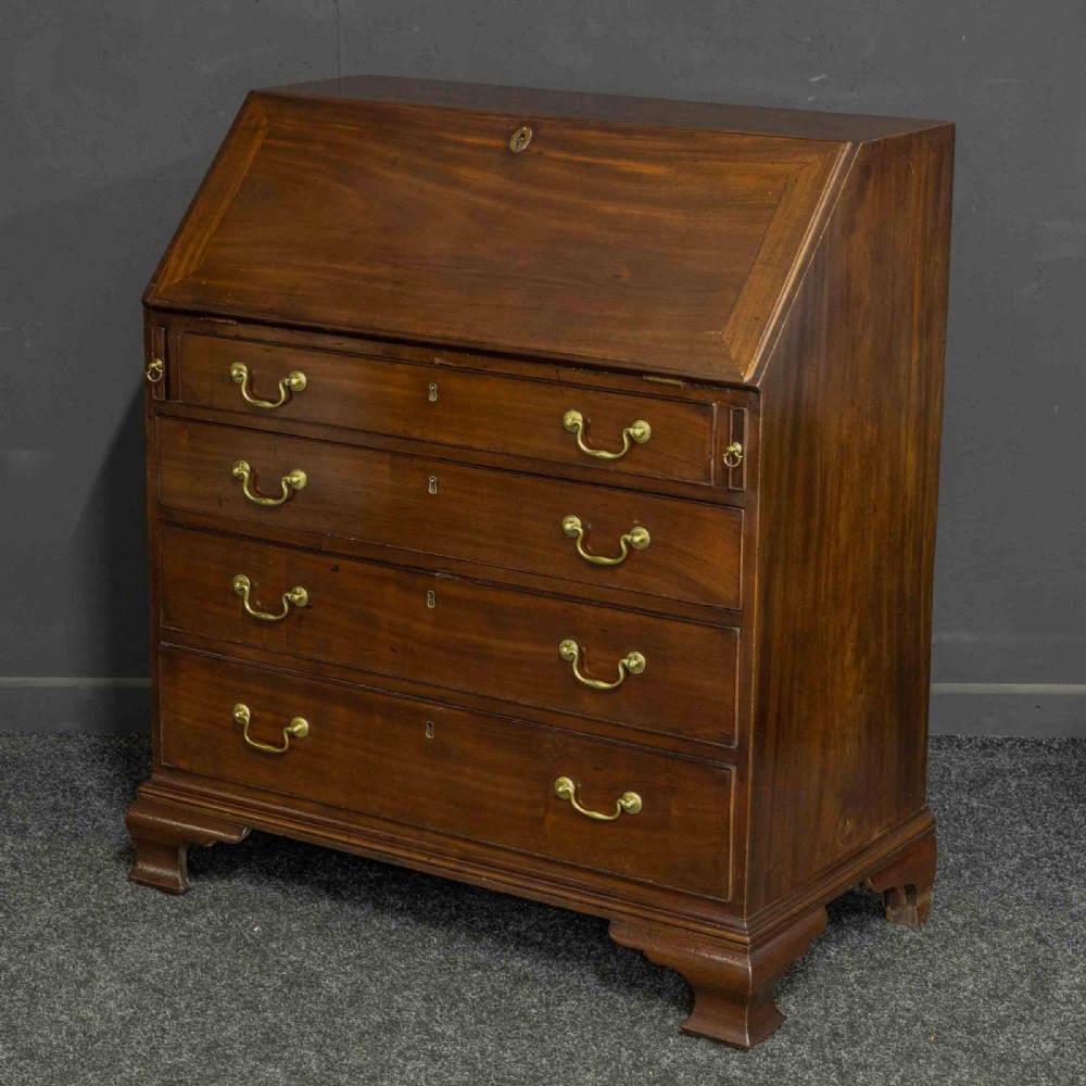 A Georgian mahogany writing bureau featuring a sloped fall-front lid above four graduated drawers with brass swan-neck handles, supported on bracket feet.