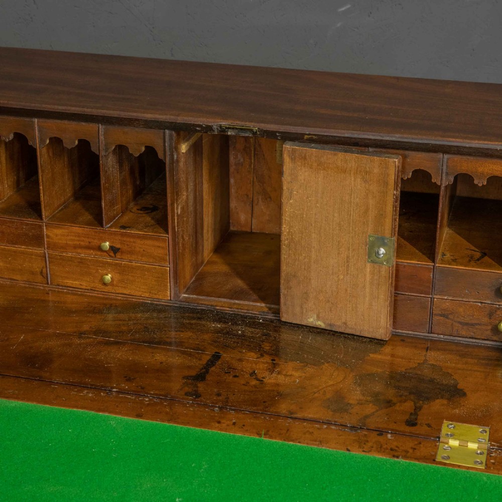 A Georgian mahogany writing bureau featuring a sloped fall-front lid above four graduated drawers with brass swan-neck handles, supported on bracket feet. View III