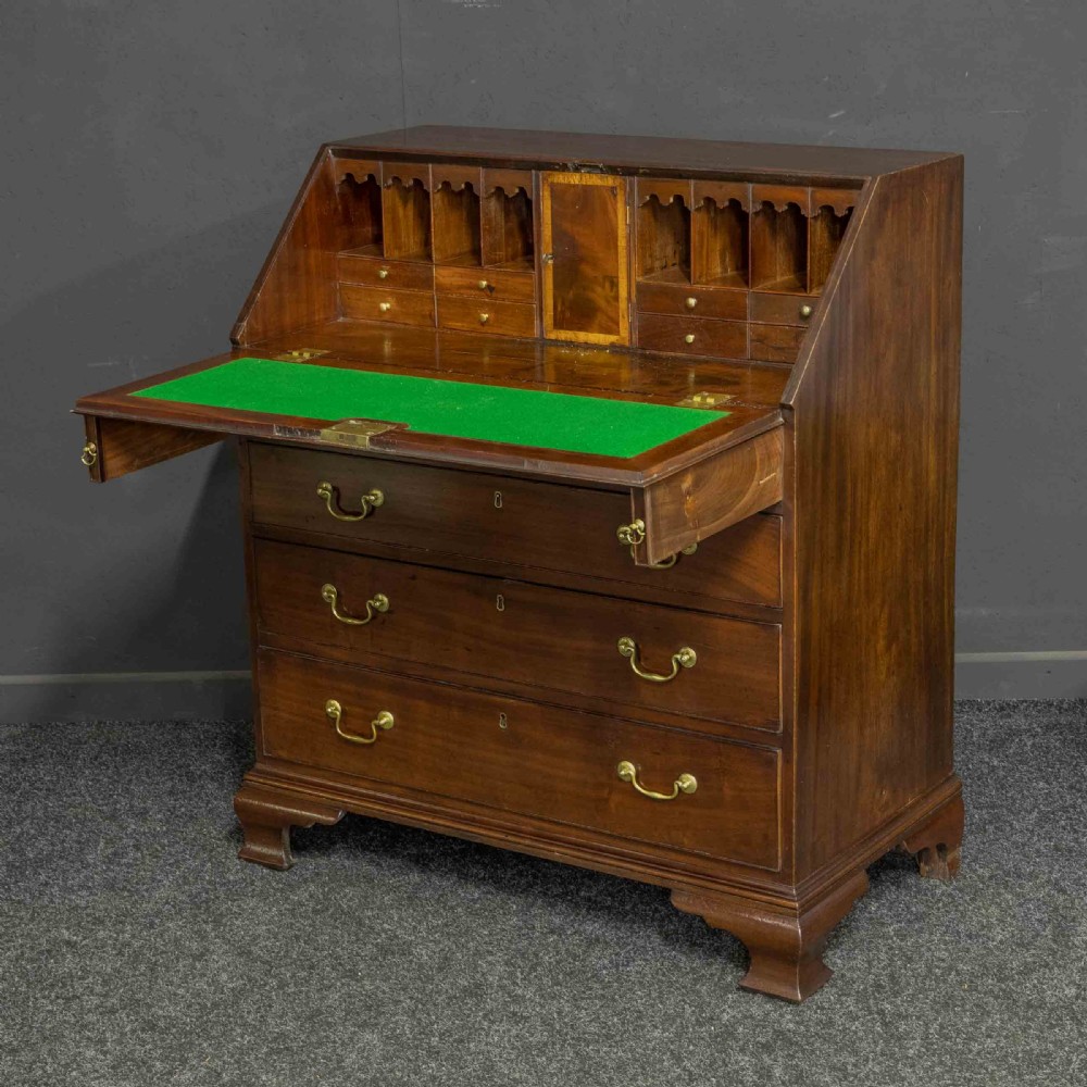 A Georgian mahogany writing bureau featuring a sloped fall-front lid above four graduated drawers with brass swan-neck handles, supported on bracket feet. View IV