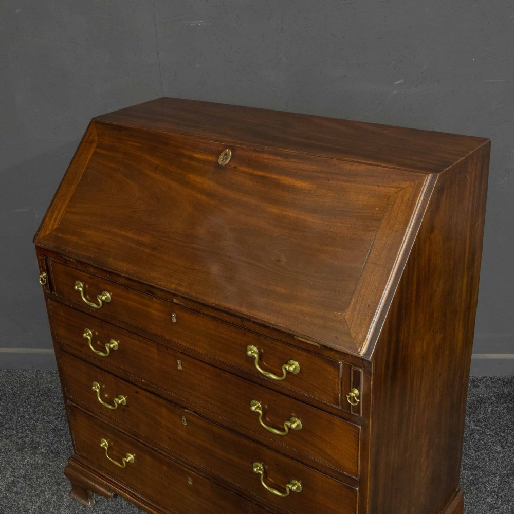 A Georgian mahogany writing bureau featuring a sloped fall-front lid above four graduated drawers with brass swan-neck handles, supported on bracket feet. View VIII