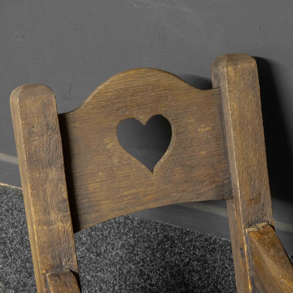 A large dark timber ducking stool featuring a long lever beam, a seated wooden chair at one end, and a heavy support frame on wooden wheels. View VII