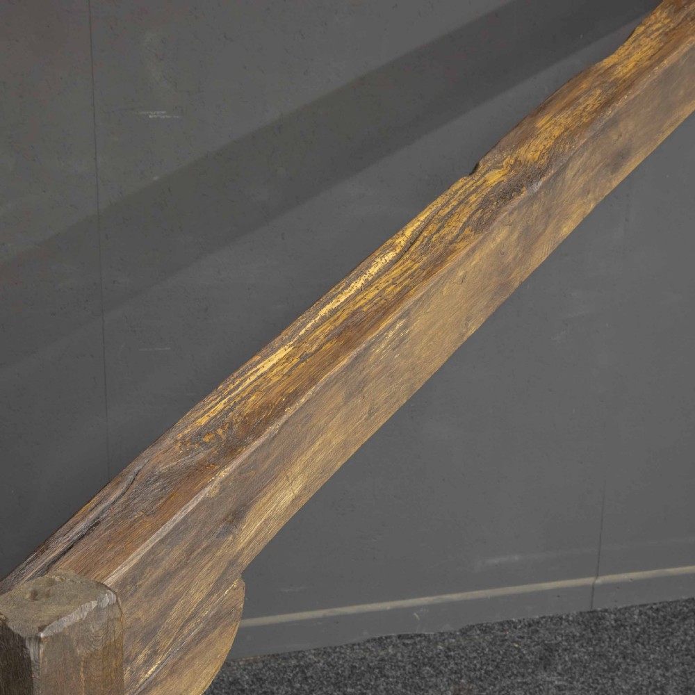 A large dark timber ducking stool featuring a long lever beam, a seated wooden chair at one end, and a heavy support frame on wooden wheels. View XII