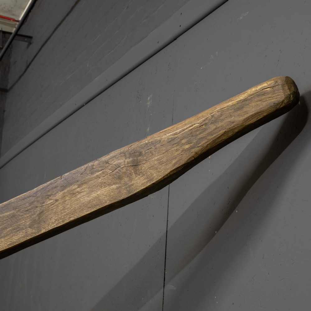 A large dark timber ducking stool featuring a long lever beam, a seated wooden chair at one end, and a heavy support frame on wooden wheels. View XIV