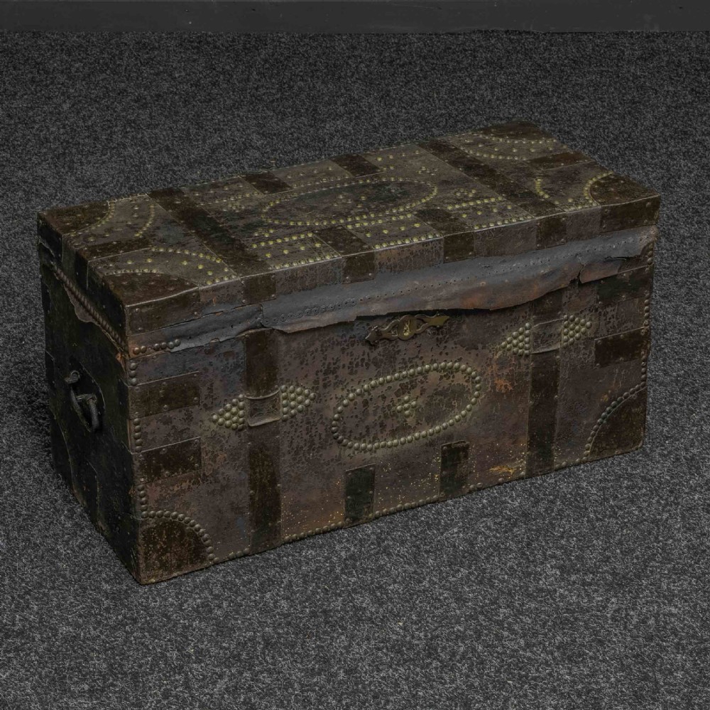 A rectangular Victorian trunk wrapped in dark brown leather with decorative brass studding, metal banding, and iron side handles.