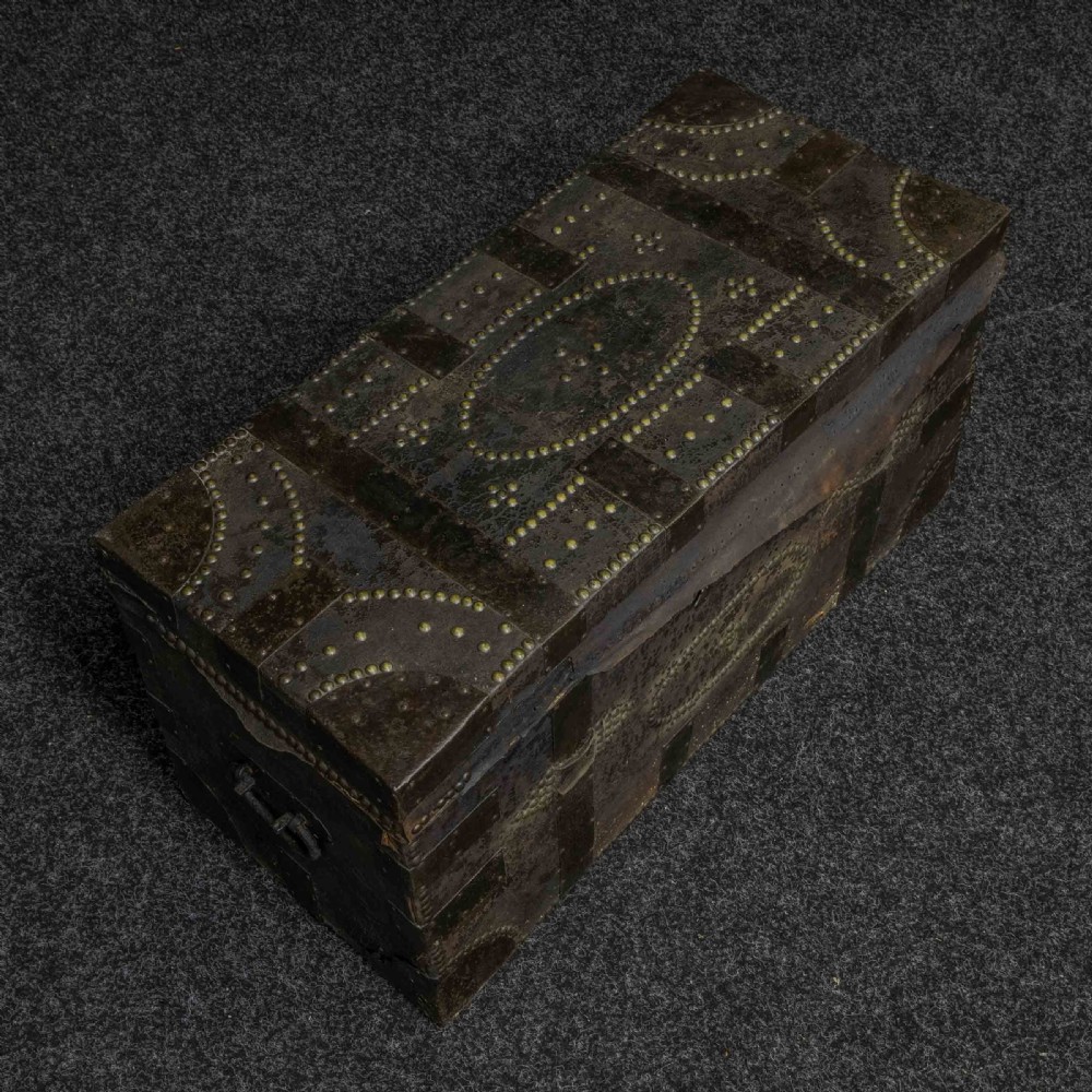 A rectangular Victorian trunk wrapped in dark brown leather with decorative brass studding, metal banding, and iron side handles. View IV