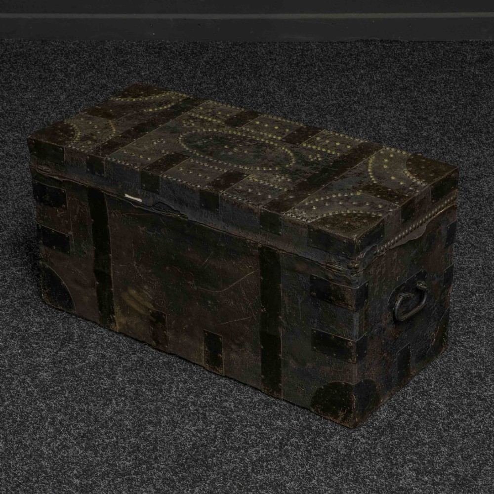A rectangular Victorian trunk wrapped in dark brown leather with decorative brass studding, metal banding, and iron side handles. View V