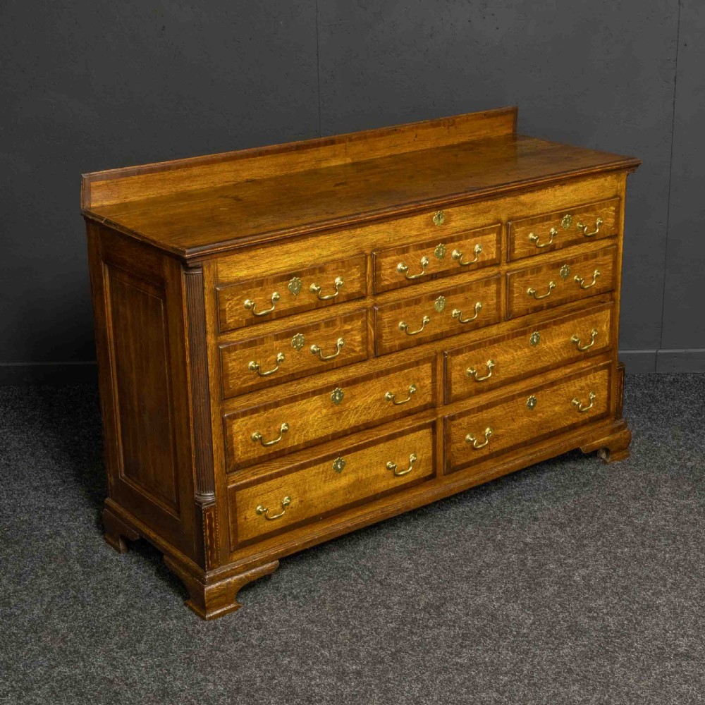 An 18th-century Georgian oak Lancashire mule chest with crossbanded drawer fronts, brass swan-neck handles, and bracket feet.