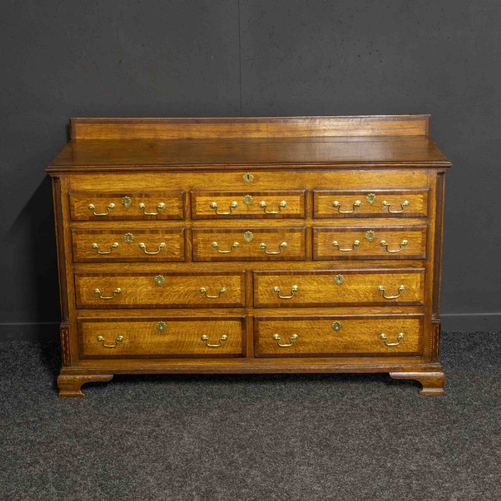 An 18th-century Georgian oak Lancashire mule chest with crossbanded drawer fronts, brass swan-neck handles, and bracket feet. View II