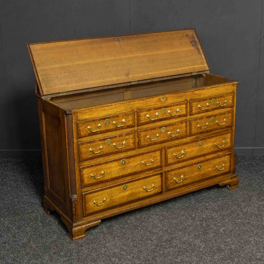 An 18th-century Georgian oak Lancashire mule chest with crossbanded drawer fronts, brass swan-neck handles, and bracket feet. View VI