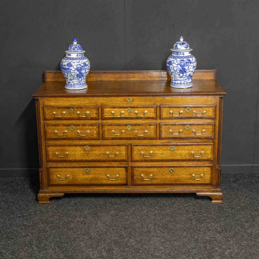 An 18th-century Georgian oak Lancashire mule chest with crossbanded drawer fronts, brass swan-neck handles, and bracket feet. View VII