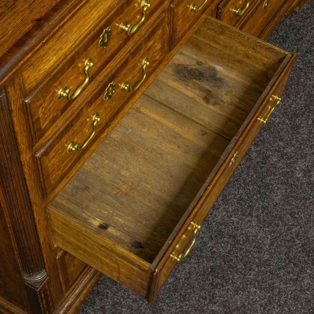 An 18th-century Georgian oak Lancashire mule chest with crossbanded drawer fronts, brass swan-neck handles, and bracket feet. View X