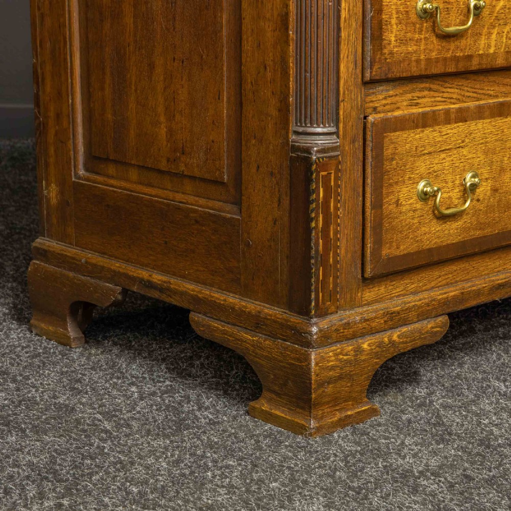 An 18th-century Georgian oak Lancashire mule chest with crossbanded drawer fronts, brass swan-neck handles, and bracket feet. View XV