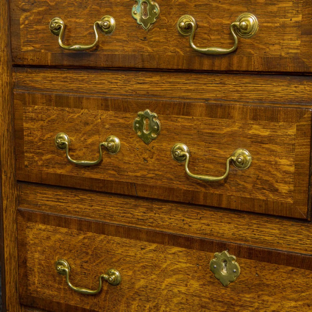 An 18th-century Georgian oak Lancashire mule chest with crossbanded drawer fronts, brass swan-neck handles, and bracket feet. View XVI