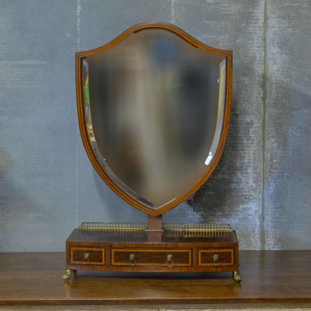 An Edwardian mahogany shield-shaped swing toilet mirror resting on a boxwood inlaid base with drawers and brass feet. View II