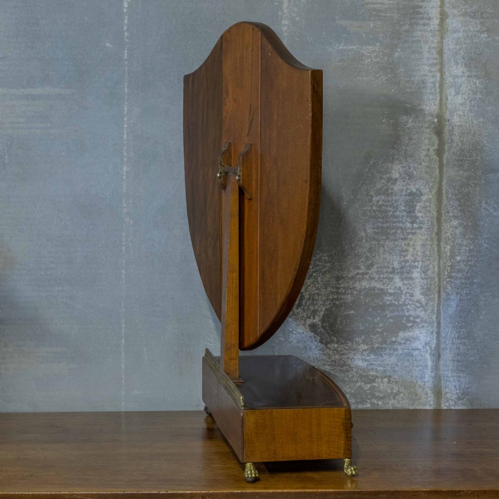 An Edwardian mahogany shield-shaped swing toilet mirror resting on a boxwood inlaid base with drawers and brass feet. View VII