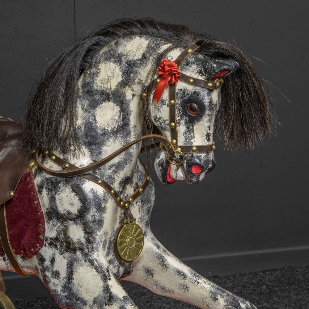 An antique Victorian hand-painted dappled grey wooden rocking horse with a leather saddle and horsehair mane mounted on an orange bow rocker. View VIII
