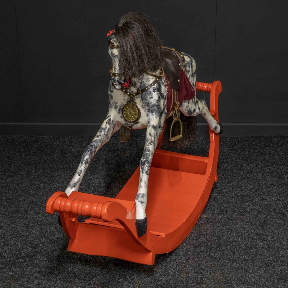 An antique Victorian hand-painted dappled grey wooden rocking horse with a leather saddle and horsehair mane mounted on an orange bow rocker. View IX