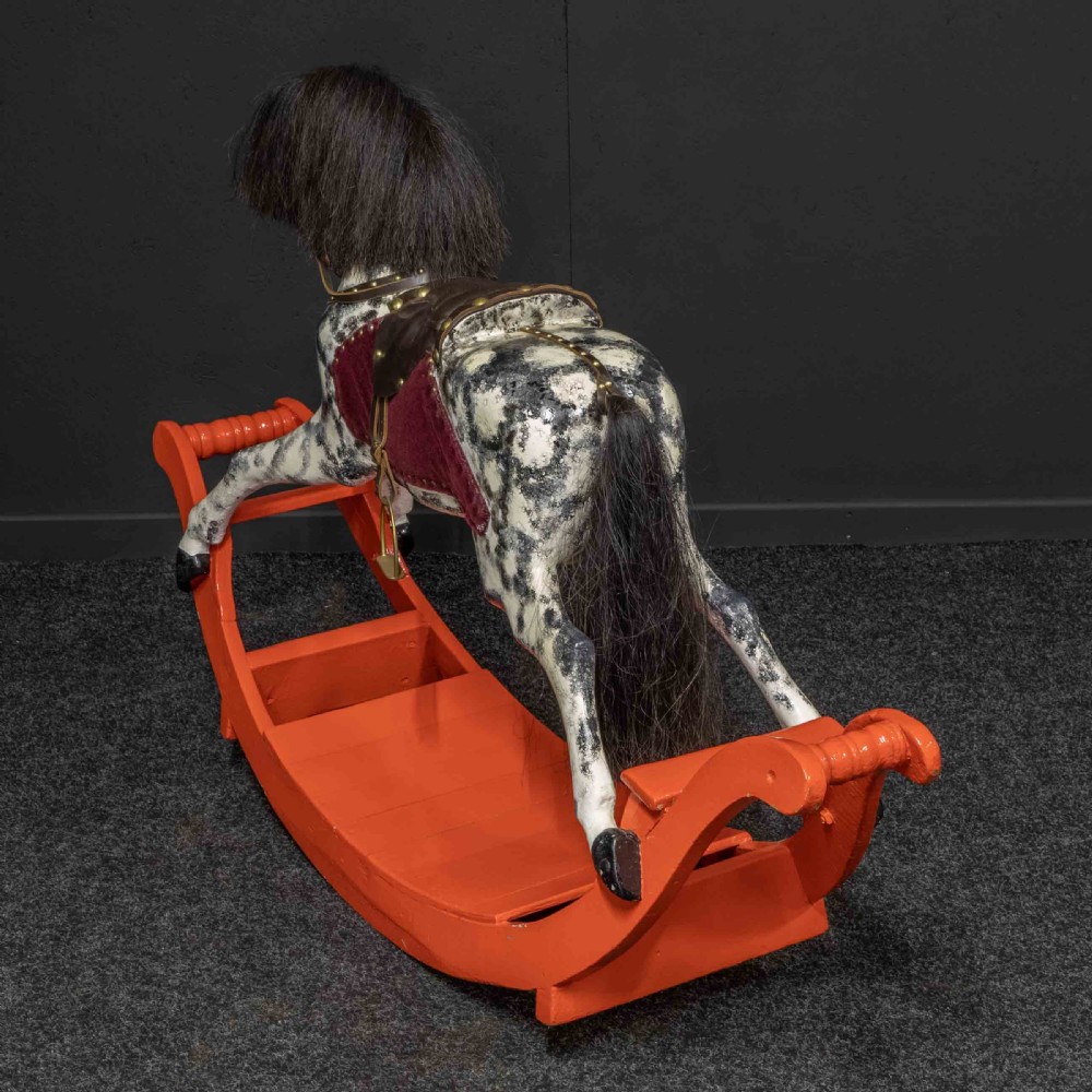 An antique Victorian hand-painted dappled grey wooden rocking horse with a leather saddle and horsehair mane mounted on an orange bow rocker. View XII
