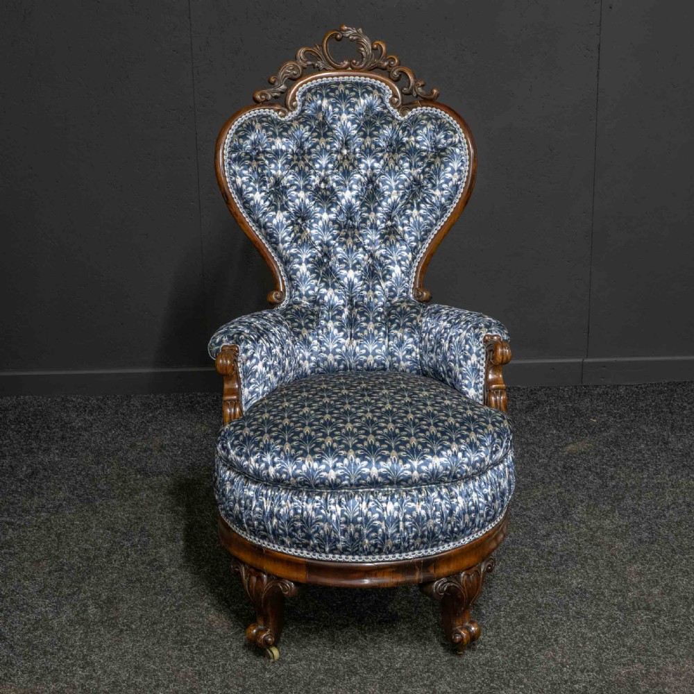 A pair of Victorian armchairs with carved timber frames, blue patterned button-back fabric upholstery, and rounded seat cushions on brass castors. View VII