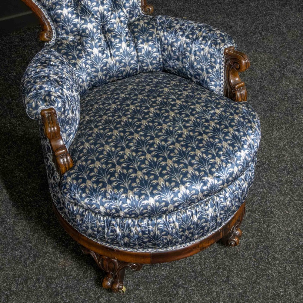 A pair of Victorian armchairs with carved timber frames, blue patterned button-back fabric upholstery, and rounded seat cushions on brass castors. View VIII