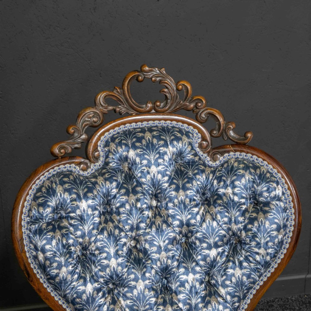 A pair of Victorian armchairs with carved timber frames, blue patterned button-back fabric upholstery, and rounded seat cushions on brass castors. View IX