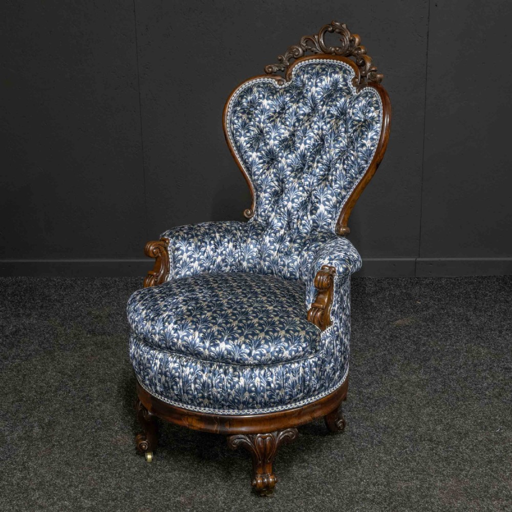 A pair of Victorian armchairs with carved timber frames, blue patterned button-back fabric upholstery, and rounded seat cushions on brass castors. View XI