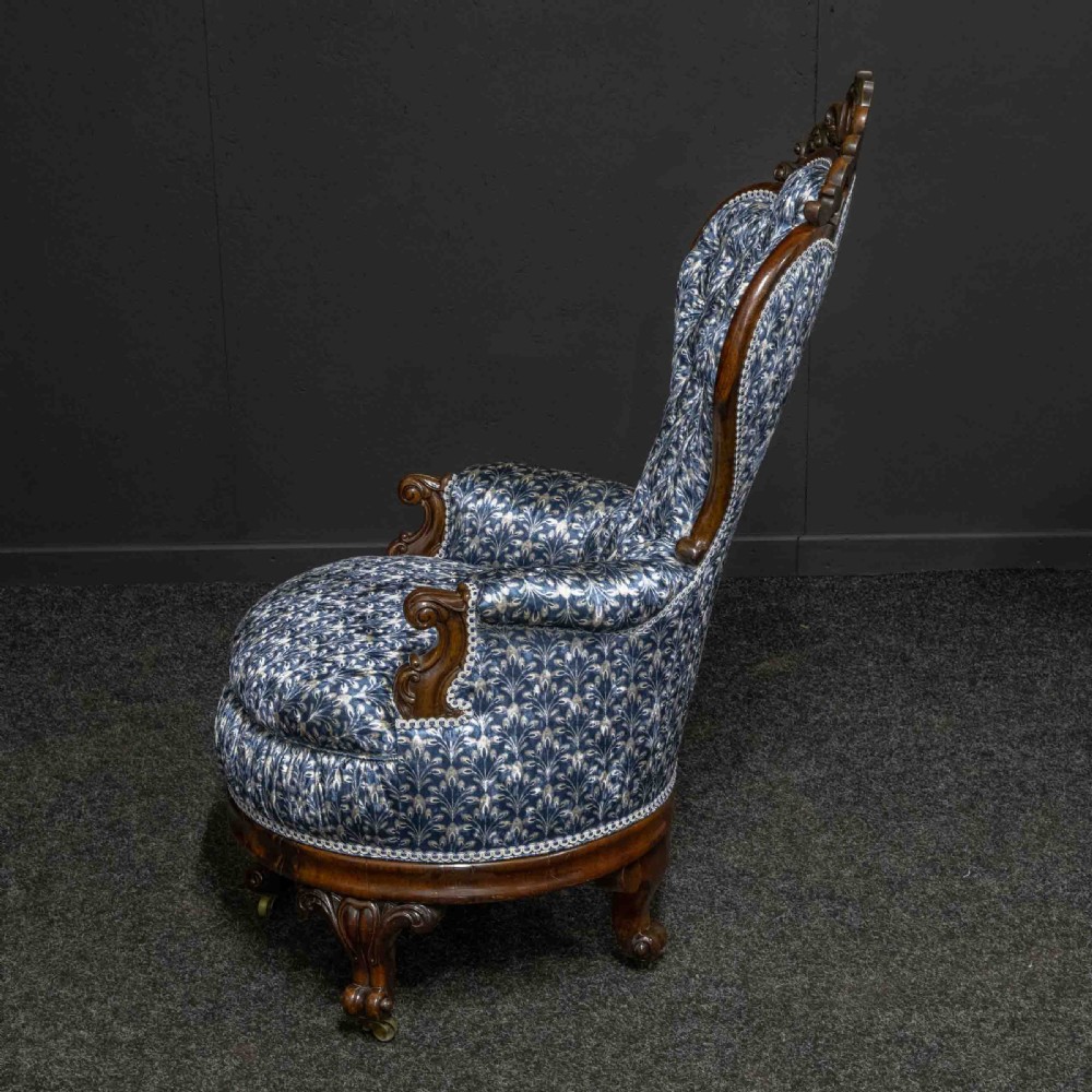 A pair of Victorian armchairs with carved timber frames, blue patterned button-back fabric upholstery, and rounded seat cushions on brass castors. View XII