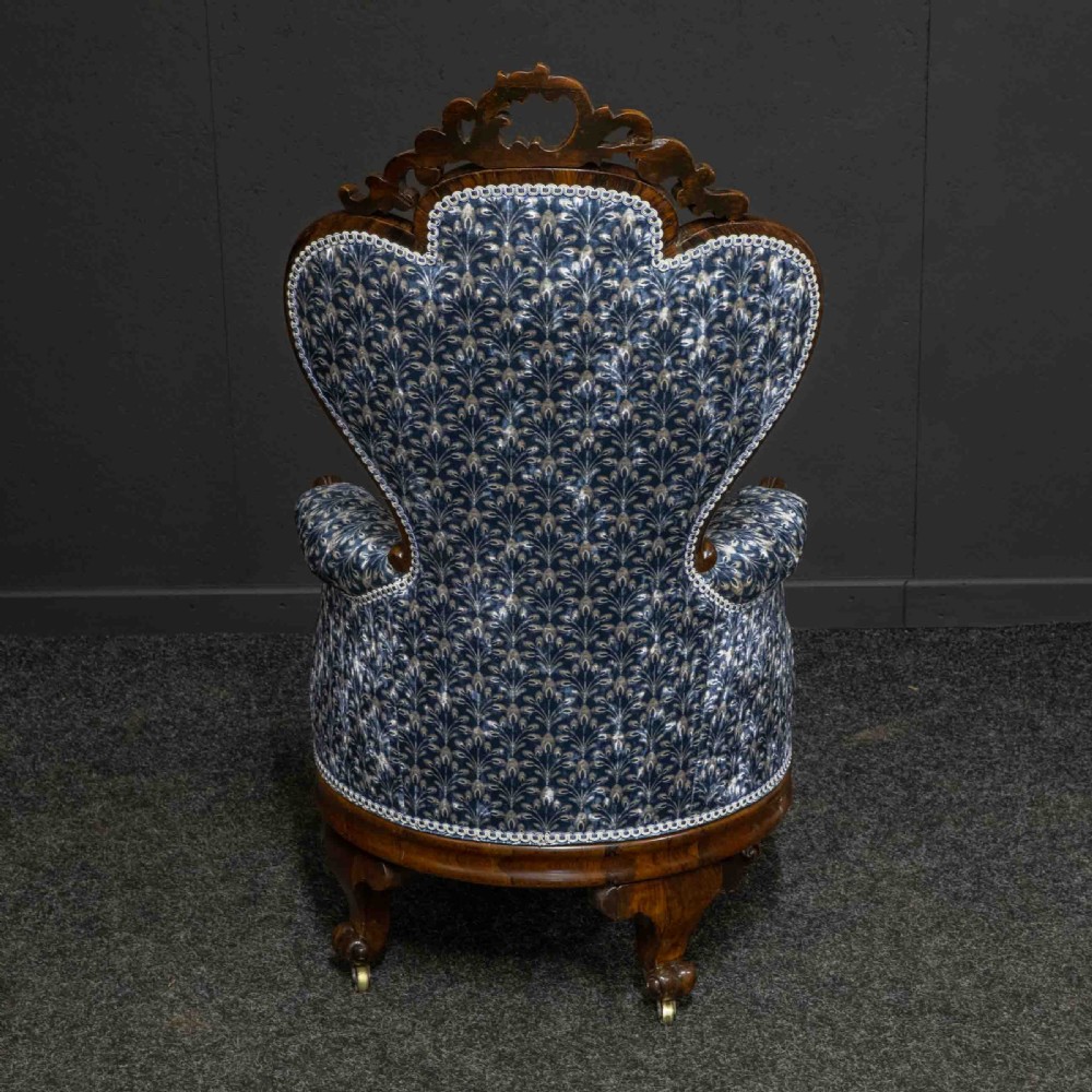A pair of Victorian armchairs with carved timber frames, blue patterned button-back fabric upholstery, and rounded seat cushions on brass castors. View XIII