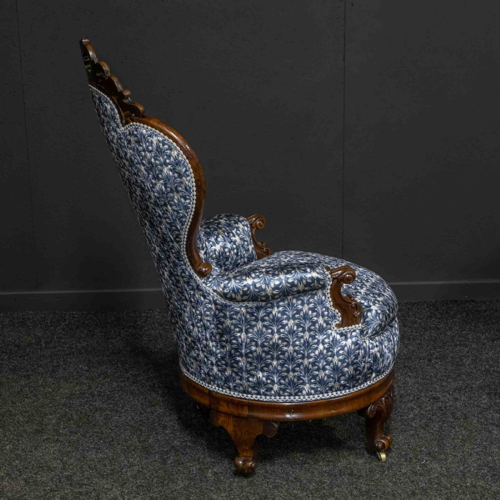 A pair of Victorian armchairs with carved timber frames, blue patterned button-back fabric upholstery, and rounded seat cushions on brass castors. View XIV