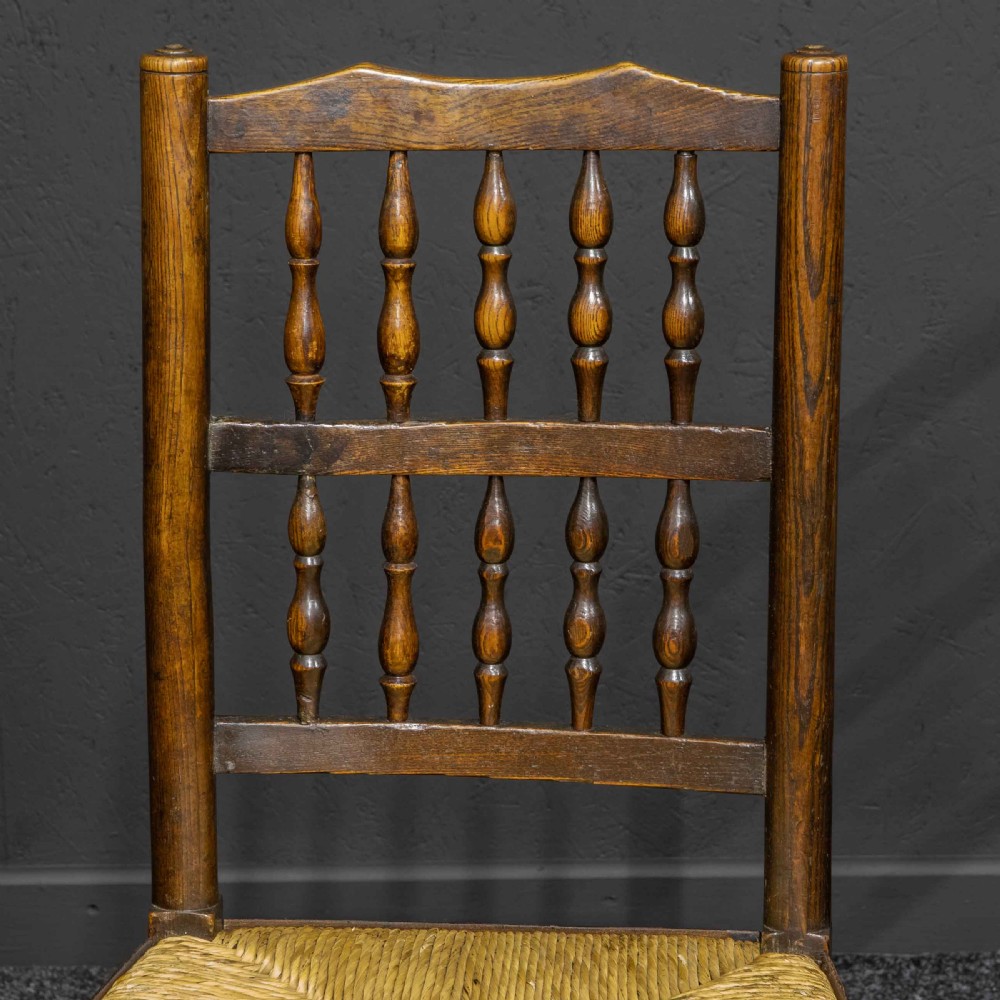 A set of eight dark oak Lancashire spindleback dining chairs with hand-woven rush seats, comprising six side chairs and two carver armchairs. View III