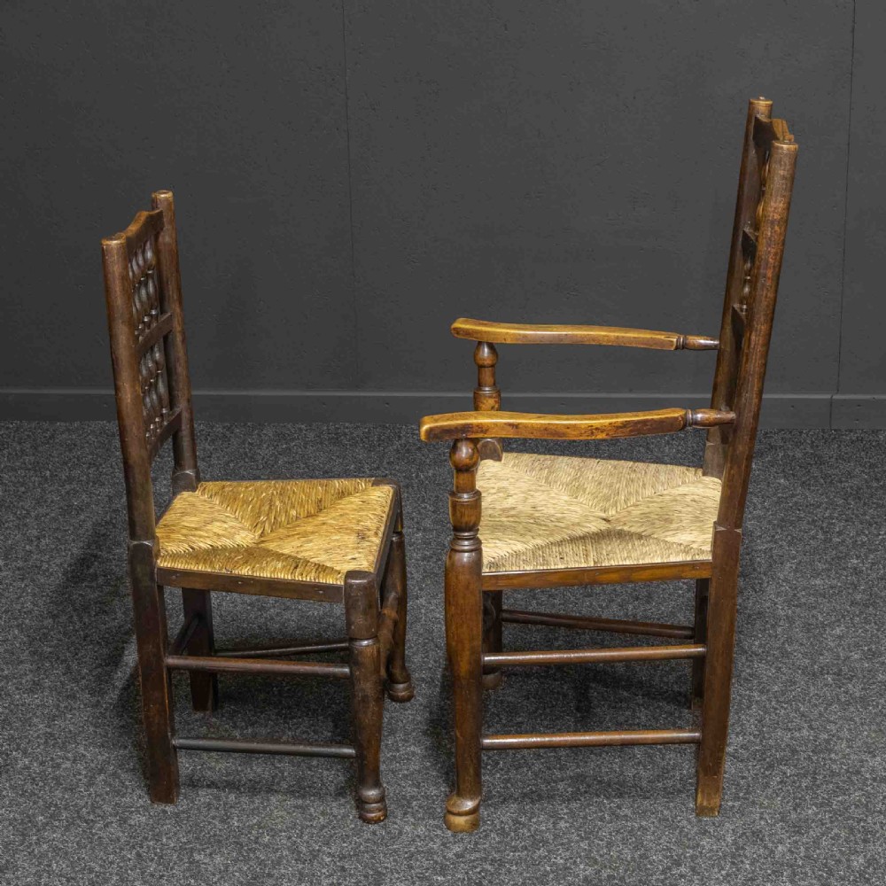 A set of eight dark oak Lancashire spindleback dining chairs with hand-woven rush seats, comprising six side chairs and two carver armchairs. View X