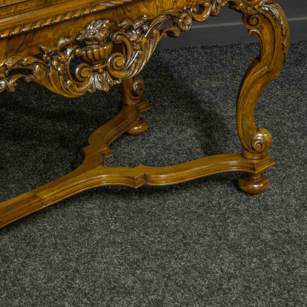A burr walnut chest on stand featuring four drawers with brass knobs, an intricately carved foliate apron, cabriole legs, and a shaped stretcher base. View IV