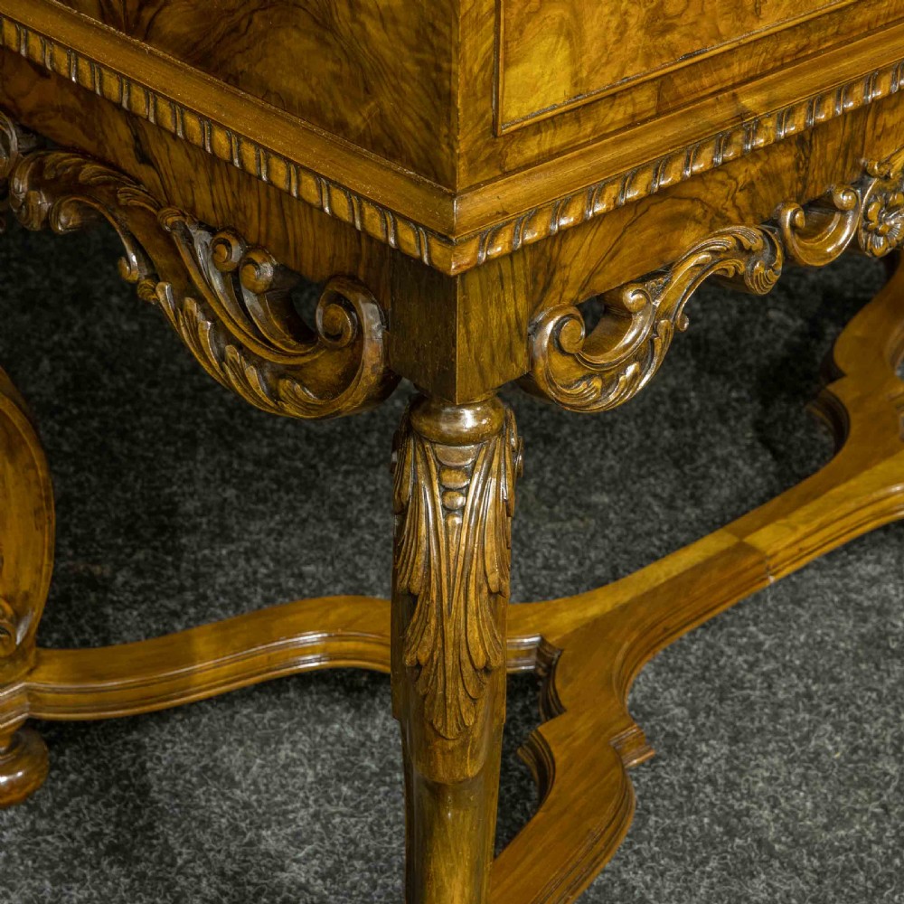 A burr walnut chest on stand featuring four drawers with brass knobs, an intricately carved foliate apron, cabriole legs, and a shaped stretcher base. View VI