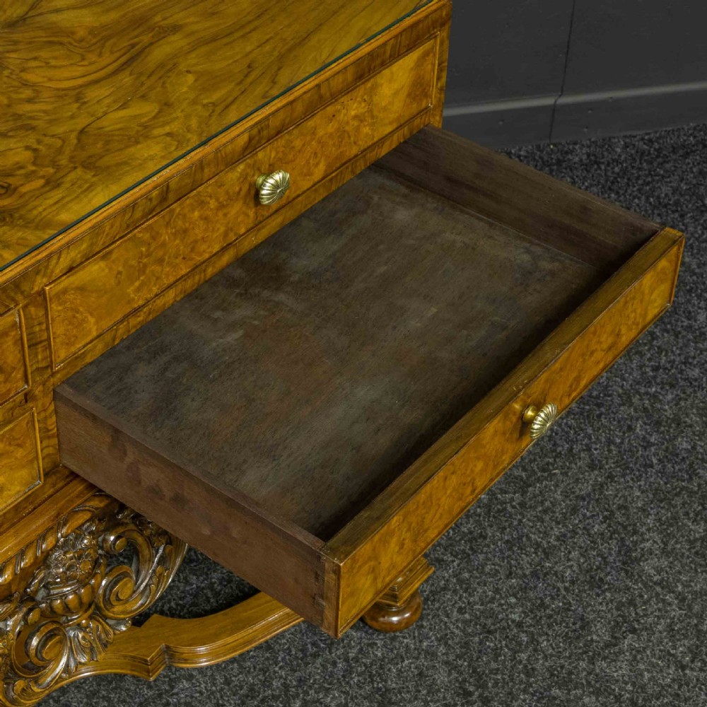 A burr walnut chest on stand featuring four drawers with brass knobs, an intricately carved foliate apron, cabriole legs, and a shaped stretcher base. View VIII