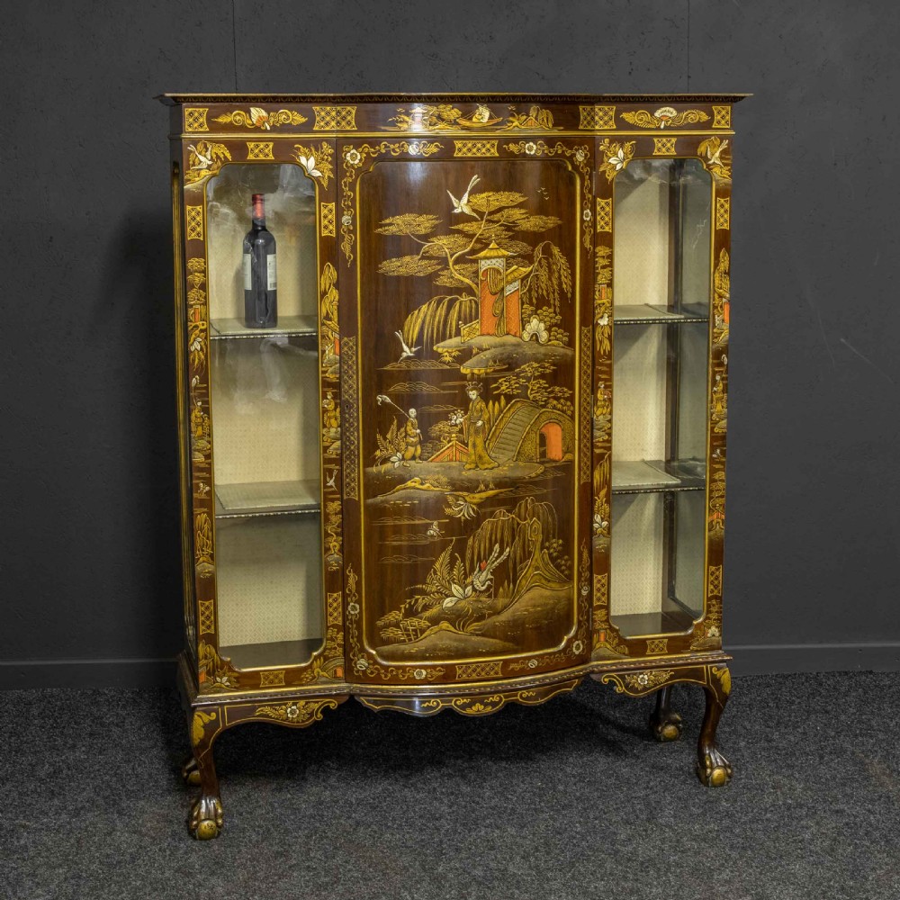An antique dark timber Chinoiserie display cabinet featuring gold lacquered oriental scenes, glazed side panels, and carved cabriole legs with ball and claw feet.