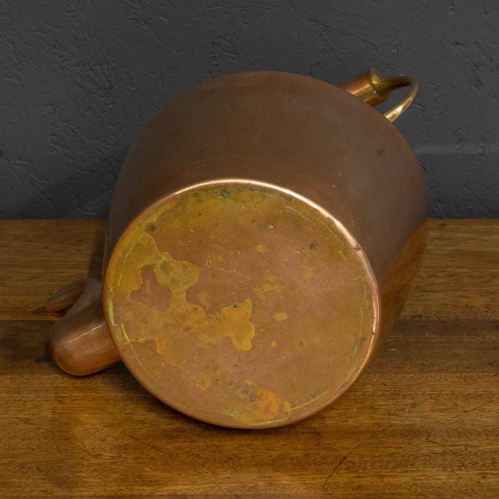 A polished Victorian copper kettle featuring a brass finial lid, a curved spout, and an overhead copper handle with brass supports. View VI