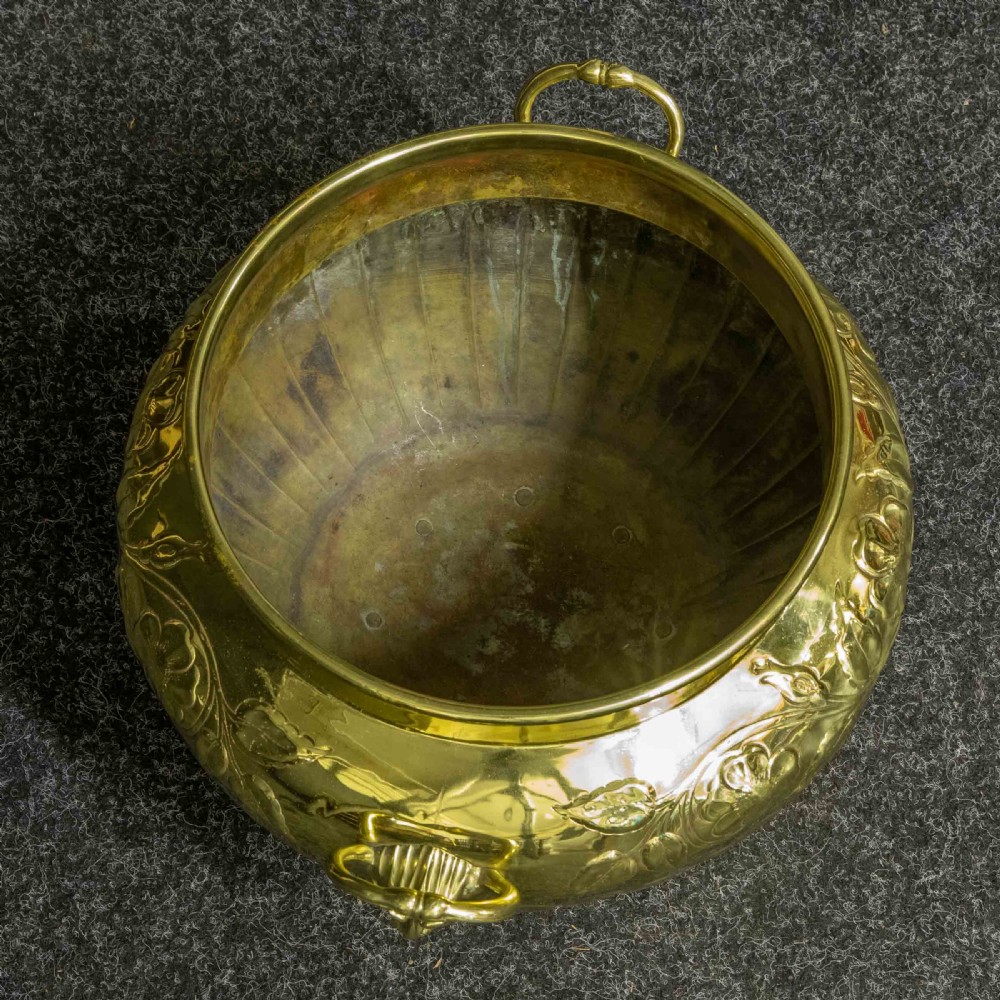 A polished brass planter featuring embossed floral motifs, gadrooned lower body detailing, twin side handles, and a raised pedestal base. View IV