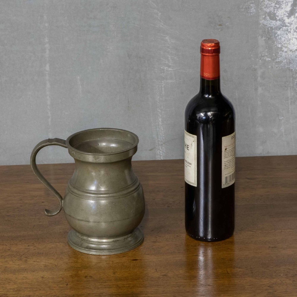 A Victorian two-pint pewter tankard with a baluster-shaped body, flared rim, curved handle, and circular pedestal base. View VI