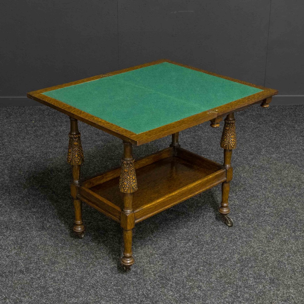A dark oak two-tier tea trolley with carved turned legs, a galleried top tray, and metal castors. View IV