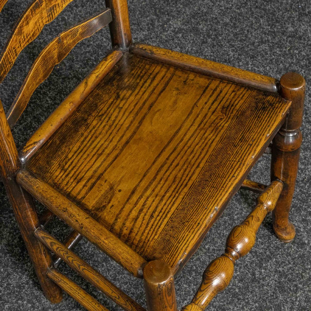 A set of eight Georgian oak dining chairs featuring wavy ladderback splats, solid wooden seats, and turned front stretchers. View II