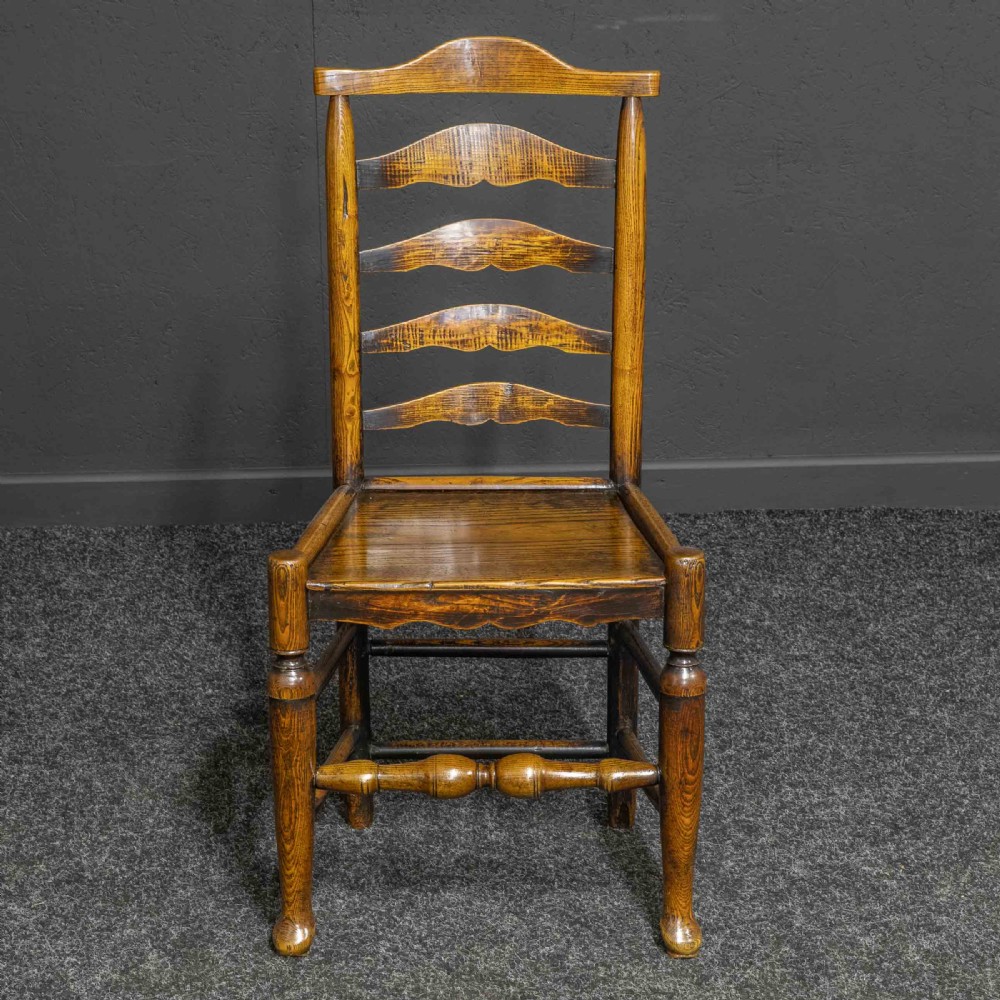 A set of eight Georgian oak dining chairs featuring wavy ladderback splats, solid wooden seats, and turned front stretchers. View III