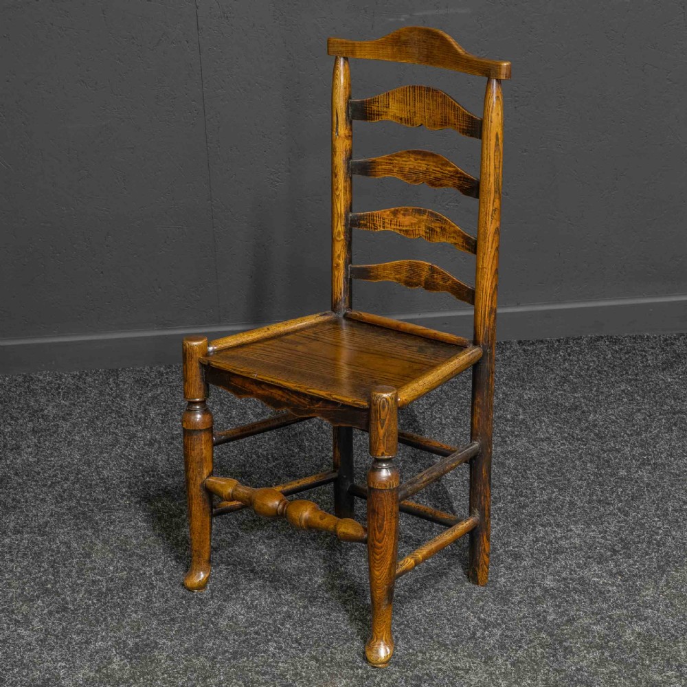 A set of eight Georgian oak dining chairs featuring wavy ladderback splats, solid wooden seats, and turned front stretchers. View IV