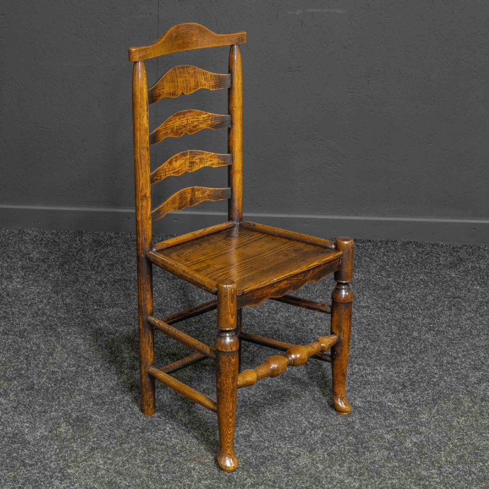 A set of eight Georgian oak dining chairs featuring wavy ladderback splats, solid wooden seats, and turned front stretchers. View V