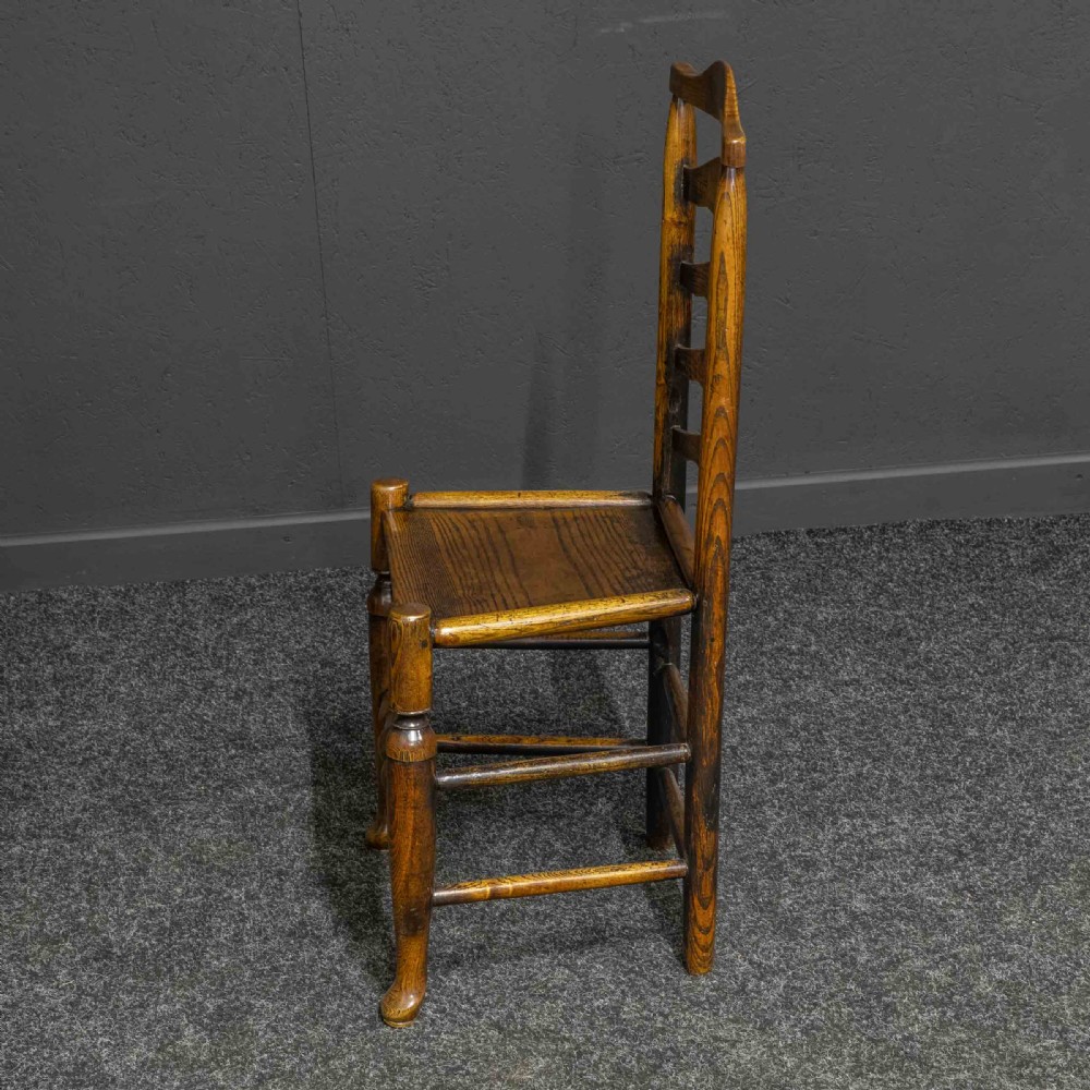 A set of eight Georgian oak dining chairs featuring wavy ladderback splats, solid wooden seats, and turned front stretchers. View VI