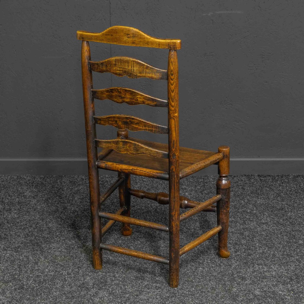 A set of eight Georgian oak dining chairs featuring wavy ladderback splats, solid wooden seats, and turned front stretchers. View VIII
