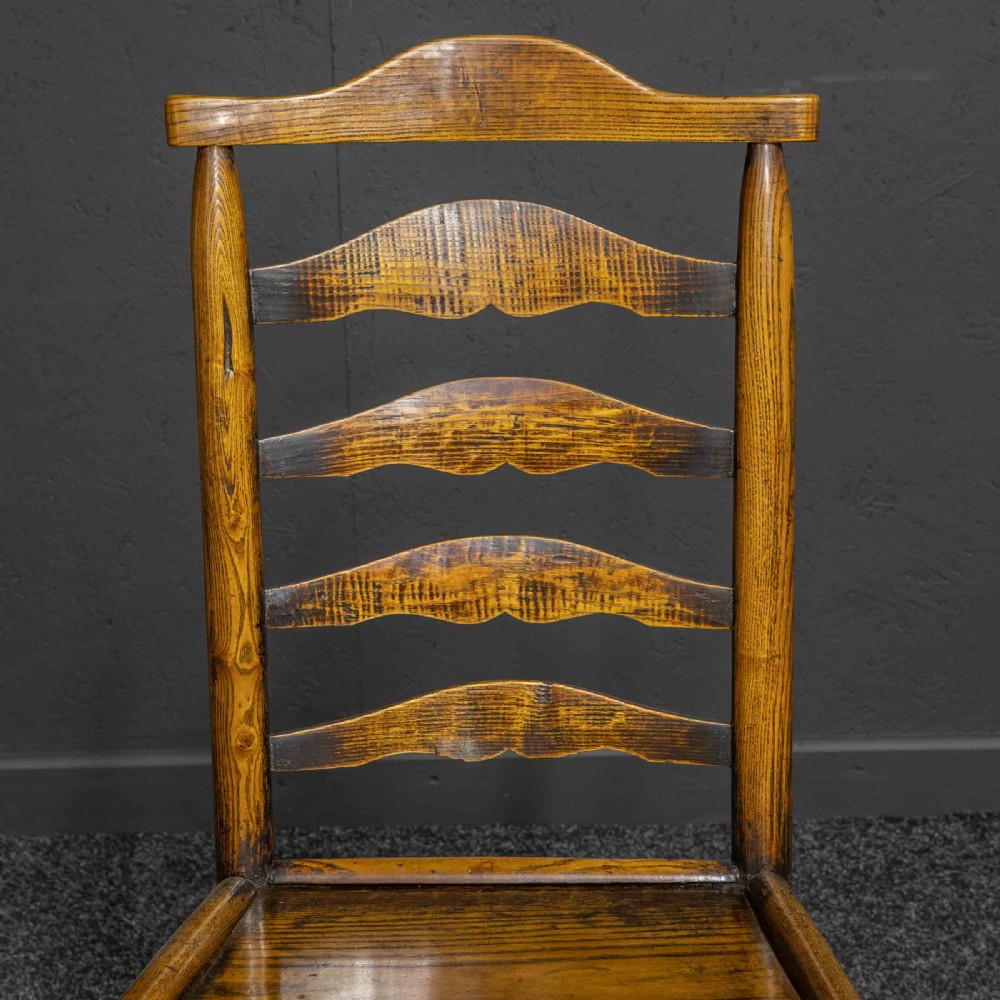 A set of eight Georgian oak dining chairs featuring wavy ladderback splats, solid wooden seats, and turned front stretchers. View XI