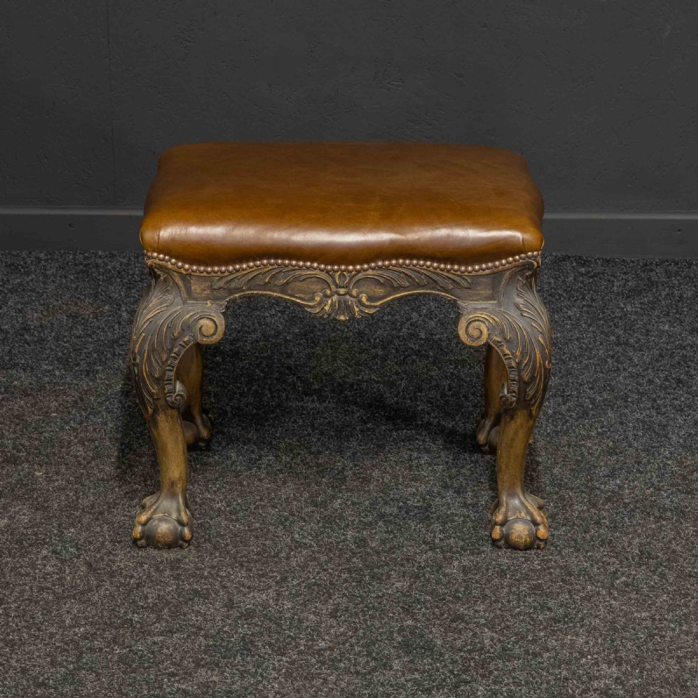A low Chippendale style stool featuring a brown leather upholstered seat with brass stud detailing and dark carved cabriole legs ending in claw and ball feet. View II