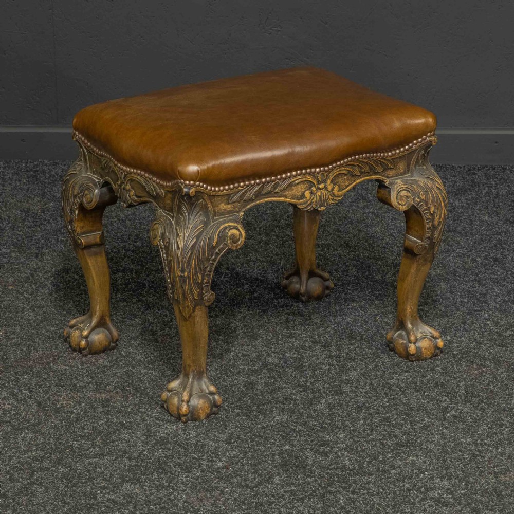 A low Chippendale style stool featuring a brown leather upholstered seat with brass stud detailing and dark carved cabriole legs ending in claw and ball feet. View III